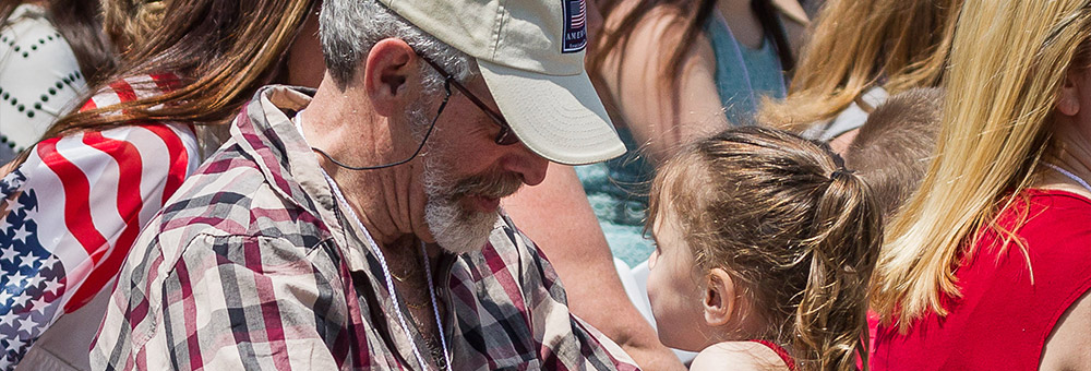 Older male veteran sitting at the menorial looking at his grandaughter